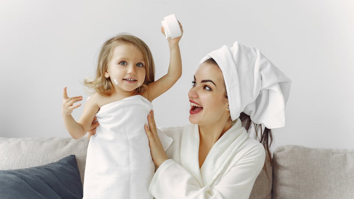 A joyful mother and daughter enjoying a playful moment indoors with towels.